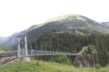 Steel rope suspenion bridge spanning the gorge in a mountain landscape