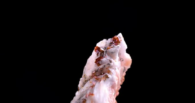 orange vanadinite on baryte rotating 360&deg; in 4k isolated on black background. macro detail close-up rough raw unpolished semi-precious gemstone.
