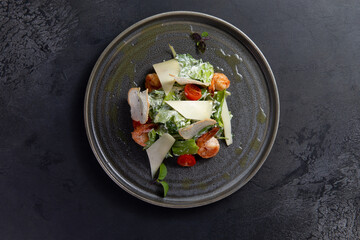 Salad with tomato and shrimp on a dark background.