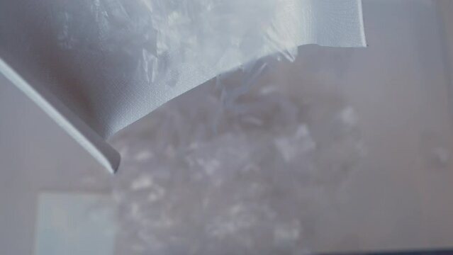 Recycling of household plastic. Shredded pieces of plastic film are moved along the production line. Modern production. Close-up