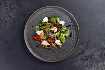 Salad with tomato and cheese on a dark background.