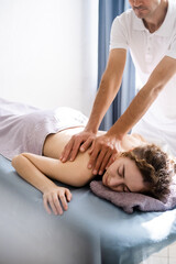 Beautiful young woman receiving body massage, vertical shoot