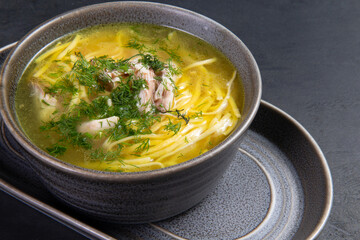 Traditional chicken noodle soup. On a dark background.