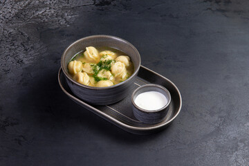 Traditional dumplings with broth. On a dark background.
