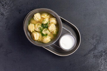 Traditional dumplings with broth. On a dark background.