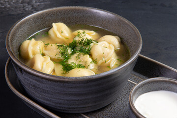 Traditional dumplings with broth. On a dark background.