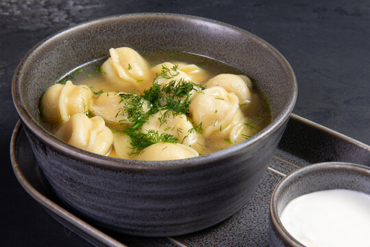 Traditional dumplings with broth. On a dark background.