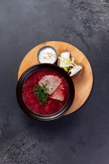 Traditional borscht soup with rye bread and lard. On a dark background.