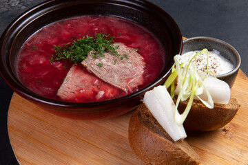 Traditional borscht soup with rye bread and lard. On a dark background.