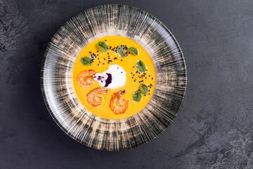 Cream soup with shrimp. On a dark background.