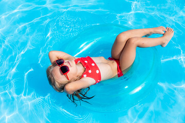 Child in swimming pool. Tropical vacation for family with kids. Little girl wearing red swimsuit...