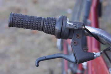 part of the bike from a black metal handlebar with a plastic handle and a brake with a cable on the gray background
