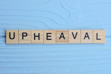 word upheaval made from wooden gray letters lies on a blue background