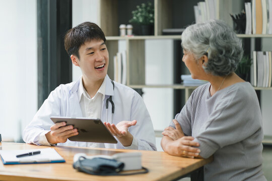 Young male doctor explaining diagnosis to senior woman patient about test results.