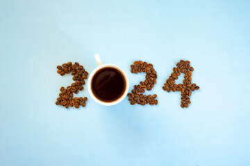 2024 number made of coffee beans and cup of coffee on light blue background as symbol of new start, goals and beginning. Happy New Year and Merry Christmas.