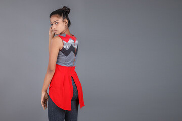 Studio shot of a young, beautiful Indian female model in casual wear wearing red and grey designer top and black jeans against white background. Female model. Fashion Portrait.