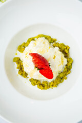 curd dessert with strawberries on top in a white plate on a marble background, side view