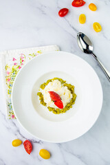 curd dessert with strawberries on top in a white plate on a marble background, side view
