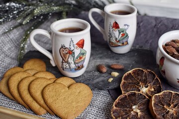Traditional Swedish mulled wine in small mugs with gnomes, heart-shaped gingerbread, dried orange slices.