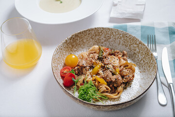 udon noodles with duck meat, herbs, sesame seeds and cherry tomatoes side view