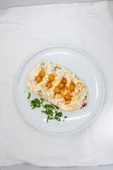 Carrot paste with yoghurt and chickpeas for decoration, served on a white plate