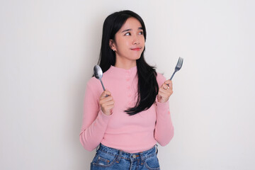 A woman looking upper left corner while holding spoon and fork