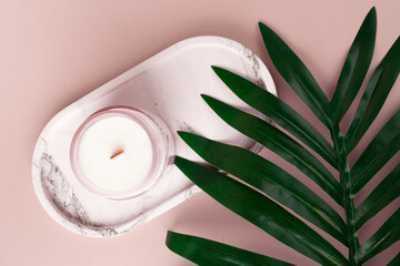 Obraz na płótnie Canvas Candle on a marble stand with a green leaf, Eco-friendly decor, Spa retreat essentials