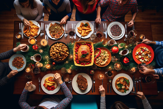 A family gathered around a dining table for a holiday Christmas meal and colorful decorations all around. Shot from a high angle to capture the sense of togetherness and celebration.