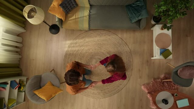 Top view capturing a young happy couple spending time together at home. They are spinning round, holding hands anf jumping up to the camera.