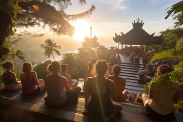 Fotobehang Bali People meditating at sunset opening chakras and inner energy at a retreat on the island of Bali sitting together and looking at a pagoda. Different nationalities in the same community 