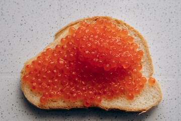 A sandwich with red caviar lies on the table. Healthy eating for weight loss bread and salmon caviar