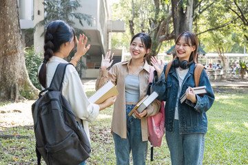 Friendly asian female college student waving hand while greeting her classmate. Education and youth lifestyle concept