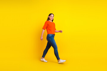 Full size body length side view profile excited young brunette woman walk go move stroll isolated on yellow background - obrazy, fototapety, plakaty