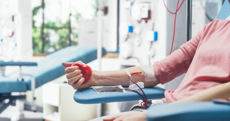 Close Up Shot Of Hand Of Female Blood Donor With an Attached Catheter. Caucasian Woman Squeezing...