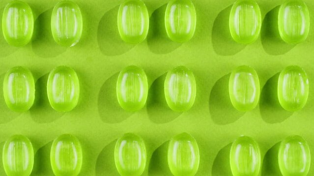 Green mint mentol lollipops, candies, bonbons disappear on purple background. Summer bright texture studio shot for store, supermarket, close up top view. Children favorite sweets made of sugar. 