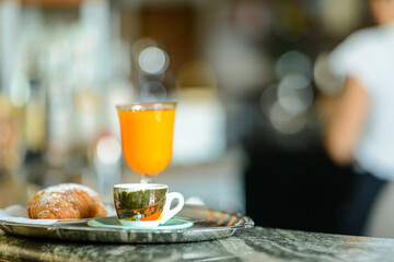 A tray with espresso coffee, orange juice and croissant brioche on bar counter in the morning