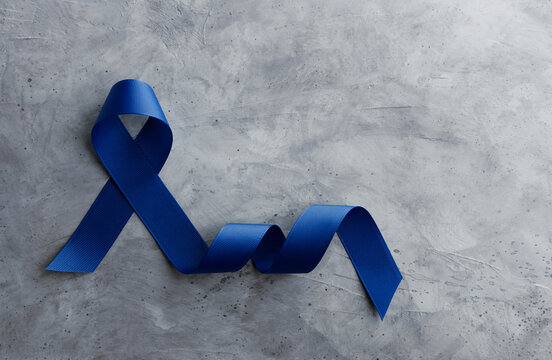 Prostate Cancer Awareness Campaign Concept. Men Healthcare. Close up of a Blue Ribbon  Lying on Rough Grey Cement Concrete background, Top View