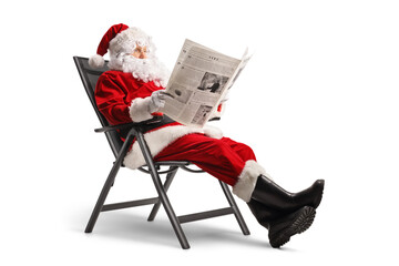Santa claus sitting in a foldable chair and reading a newspaper
