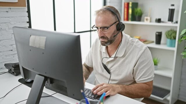 Handsome young business worker stressed, taking headphones off at the chaotic office environment