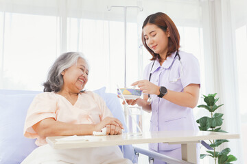 Female doctor takes care healthcare elderly patients with friendliness helping with food willingness encouraging patients to feel good supporting them in recuperating their illnesses in the hospital.