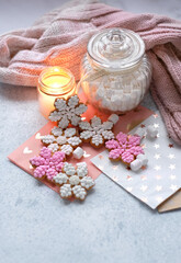 cozy Christmas background. Snowflake gingerbread cookies, candle, jar with marsmallows and knitted scarf on table. Festive winter season concept. Christmas, New year holidays