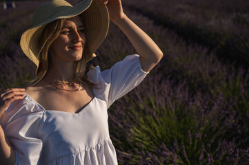 young pretty girl in a white dress in a hat on a lavender field, looking to the side. Place for inscription