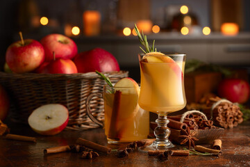 Mulled cider with apples, cinnamon, rosemary, and anise on a background of burning candles.