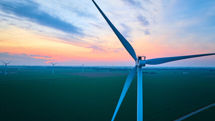 Gorgeous pinks and blues with orange glow at sunset over aerial of wind farm in farmland