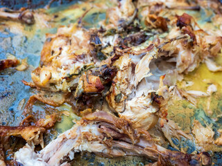 roasted chicken on a metal tray after eating the meat leftover skin bones and cold congealed fats