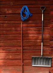 Snow shovels hanging against a red barn