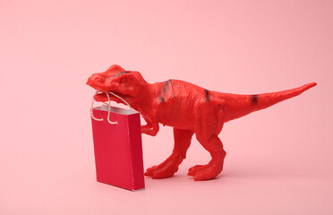 Toy tyrannosaurus with a shopping bag on a pink background. Minimalism shopping concept