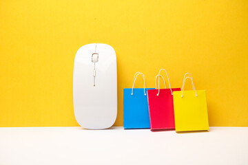 Pc mouse with Miniature shopping bags on yellow background. Online shopping