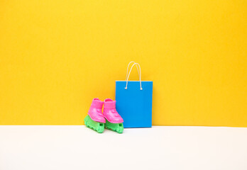 Miniature shopping bag and roller skates on yellow background