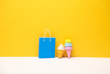 Miniature shopping bag and ice cream on yellow background